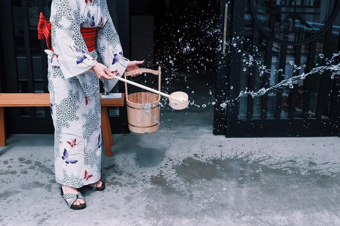 浴衣姿で打ち水をする女性